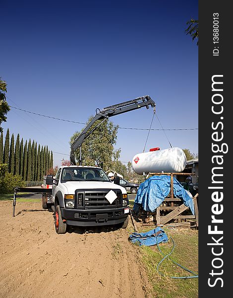 Crane in operation lifting a large gas tank