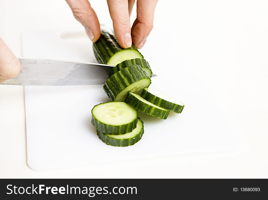 Sliced cucumber with knife on a white background