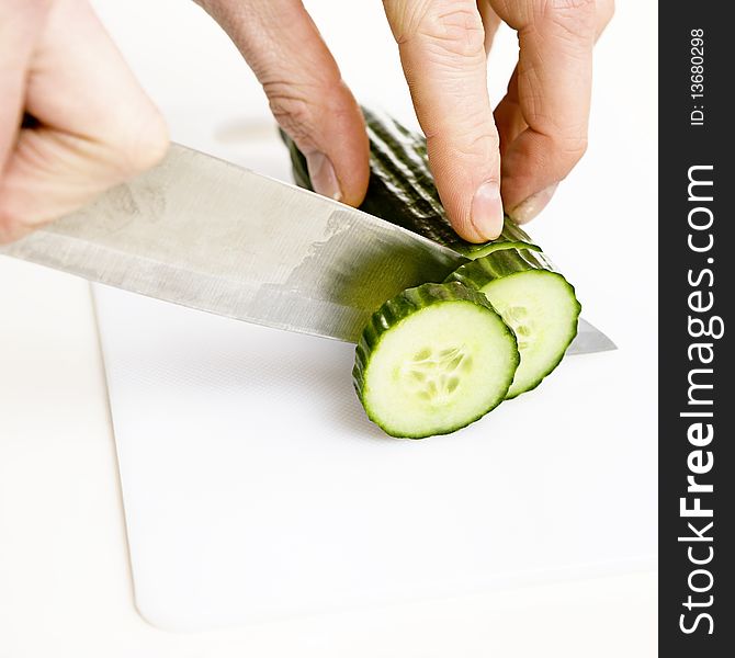 Sliced cucumber with knife on a white background