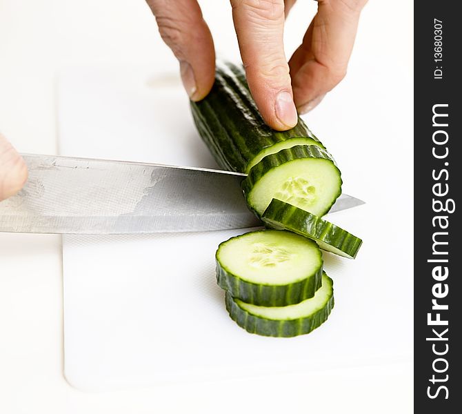 Sliced cucumber with knife on a white background