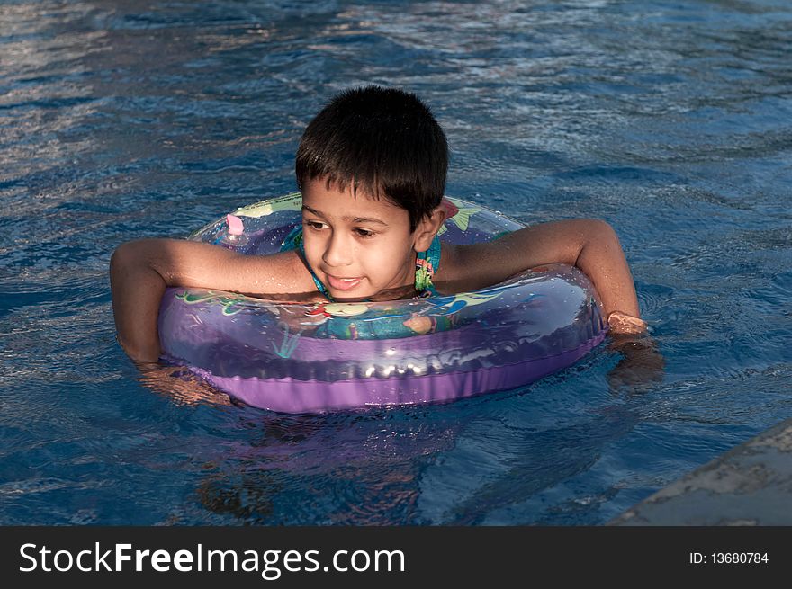 An handsome indian boy swimming happily in the pool