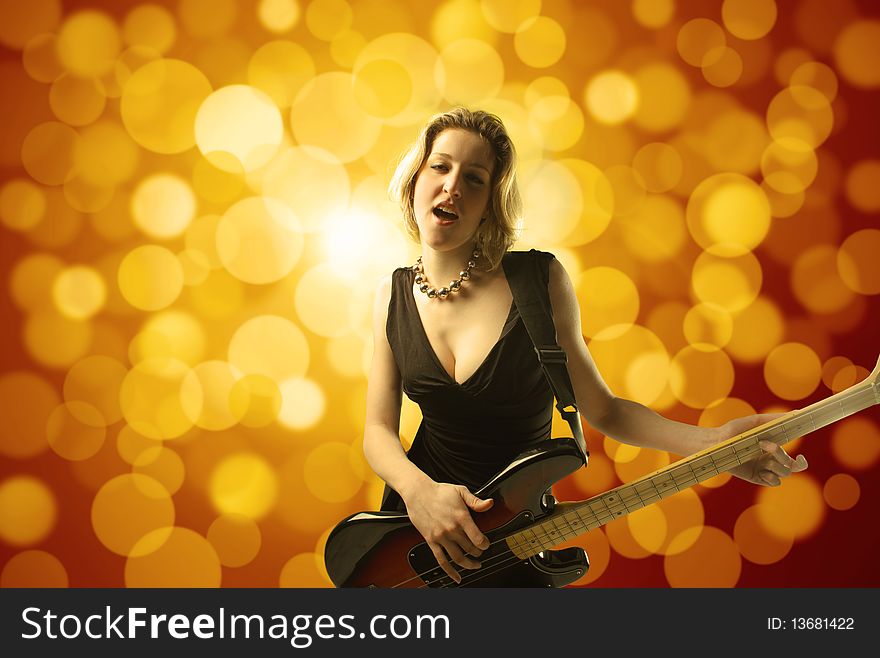 Portrait of a young woman singing and playing the bass guitar with glitters on the background. Portrait of a young woman singing and playing the bass guitar with glitters on the background