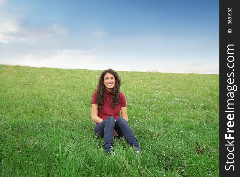 Smiling young woman sitting on a green meadow. Smiling young woman sitting on a green meadow