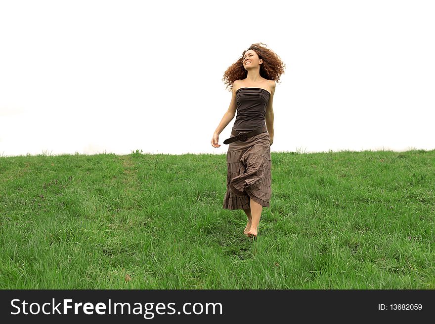 Smiling red haired woman walking on a green meadow. Smiling red haired woman walking on a green meadow