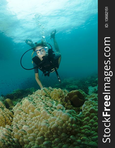 Young female scuba diver swims over coral reef