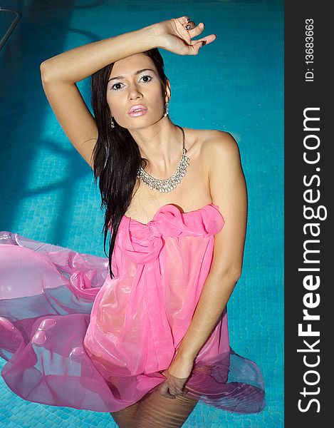 The girl in a pink fabric costs in pool and looks directly. The girl in a pink fabric costs in pool and looks directly.