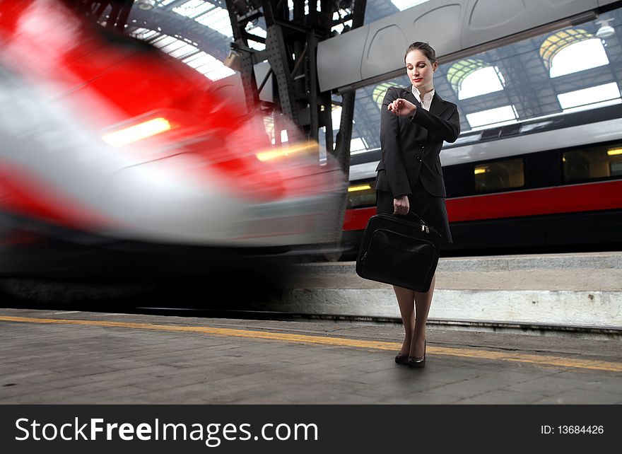 Businesswoman standing on the platform of a train station and looking at her watch. Businesswoman standing on the platform of a train station and looking at her watch