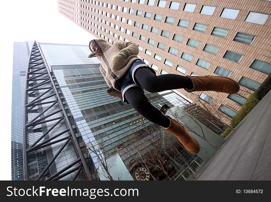 Attractive Japanese girl jumping in front of modern buildings in central Tokyo. Attractive Japanese girl jumping in front of modern buildings in central Tokyo