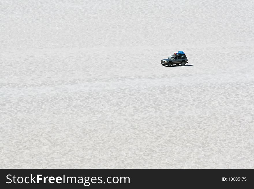 Jeep crossing the high altitude salt flats of Salar de Uyuni in Bolivian Andes. Jeep crossing the high altitude salt flats of Salar de Uyuni in Bolivian Andes