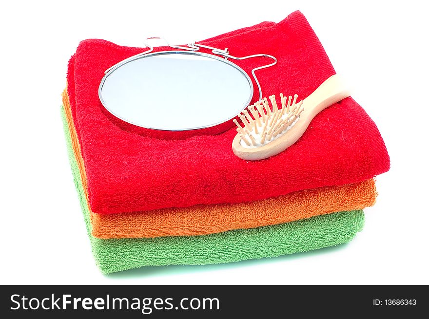 Bright fluffy towels a hairbrush and a mirror on a white background. Bright fluffy towels a hairbrush and a mirror on a white background