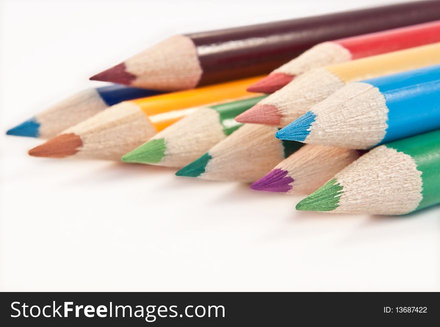 Close up capturing the ends of a selection of coloured drawing pencils arranged over white. Close up capturing the ends of a selection of coloured drawing pencils arranged over white.