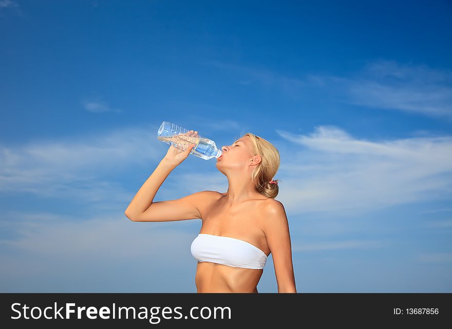 Young woman having a drink of water at the beach. Young woman having a drink of water at the beach