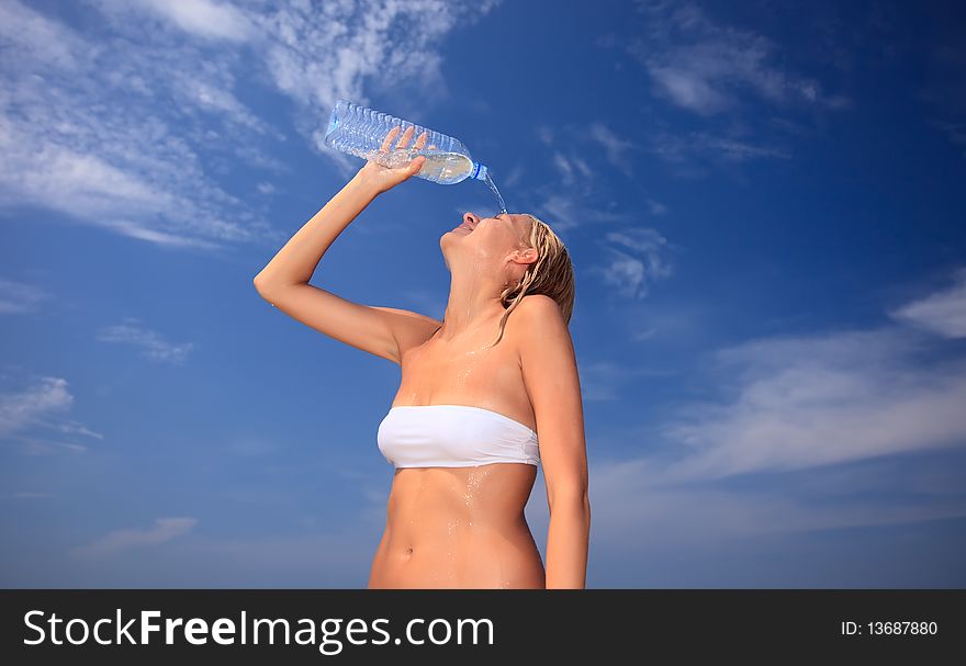 Hot woman spilling cold water. Blue sky on background.