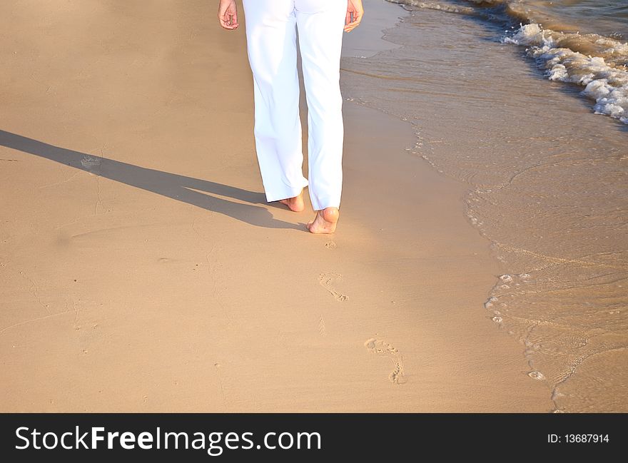 Girl waking on the beach leaving footprints on the sand. Girl waking on the beach leaving footprints on the sand