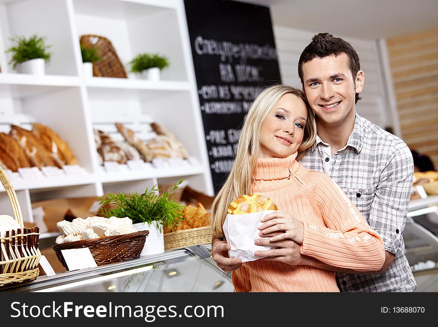 The young man embraces the girl who holds a roll. The young man embraces the girl who holds a roll