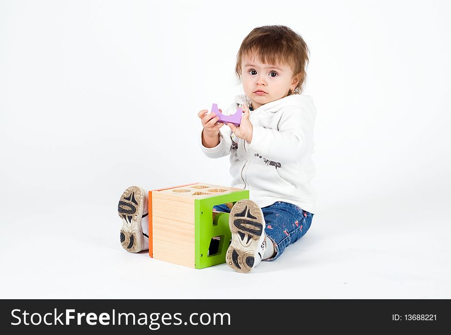 Little girl playing with wooden puzzle cube, isolated on white