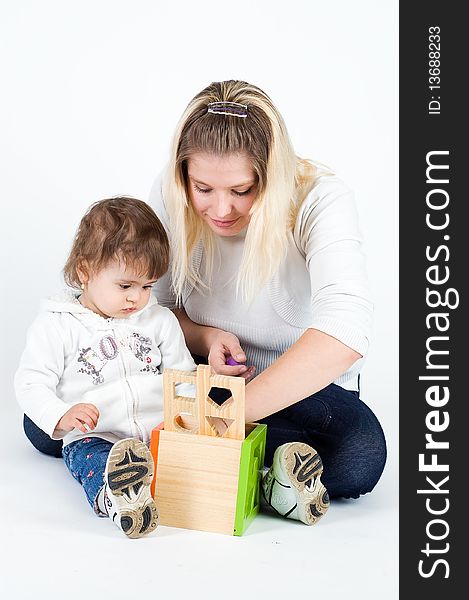 Mother and little daughter playing together with puzzle cube, isolated on white. Mother and little daughter playing together with puzzle cube, isolated on white