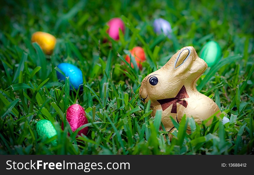 Chocolate Easter bunny and foil covered eggs in grass. Chocolate Easter bunny and foil covered eggs in grass