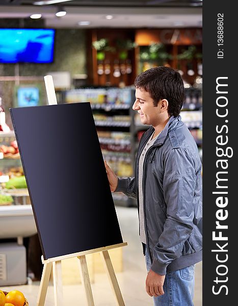 The young man faces to an empty board in shop. The young man faces to an empty board in shop