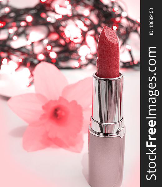 Red lipstick and pink flower on interesting background with lights