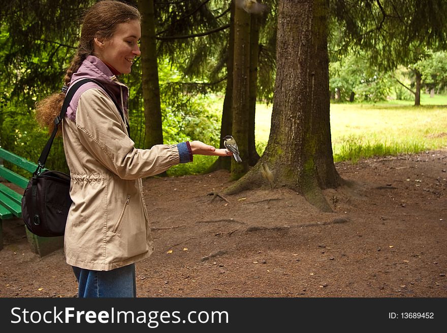 Happy girl feeding tit in the park. Happy girl feeding tit in the park