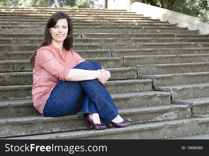 Pretty Young Woman Sitting Outside on Steps With Legs Crossed. Pretty Young Woman Sitting Outside on Steps With Legs Crossed