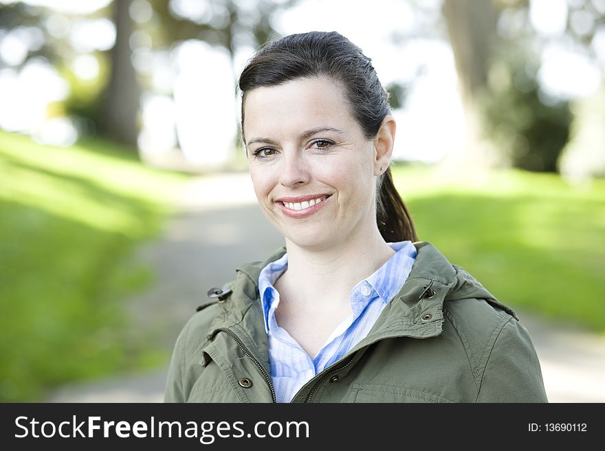 Portrait of a Pretty Young Woman Outdoors in a Park Smiling To Camera. Portrait of a Pretty Young Woman Outdoors in a Park Smiling To Camera