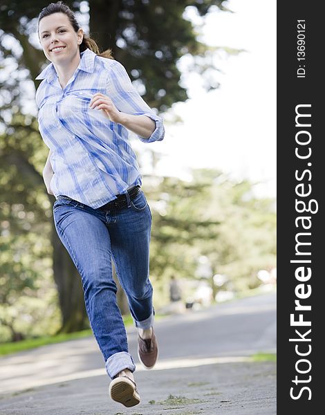 Pretty Young Woman in Jeans Running in a Park. Pretty Young Woman in Jeans Running in a Park