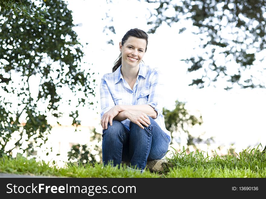 Pretty Young Woman Sitting on a Log in a Park. Pretty Young Woman Sitting on a Log in a Park