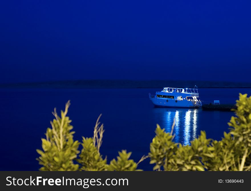 Motor yacht moored to jetty at night