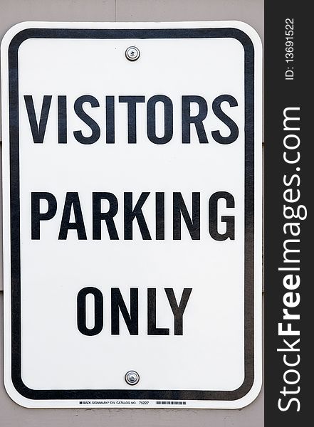 Visitors parking only sign on stucco wall