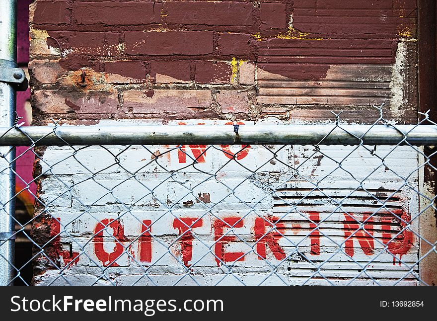 No loitering stenciled on wall behind fence. No loitering stenciled on wall behind fence