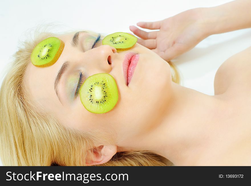 Beauty girl with kiwi on cheeks over white background. Beauty girl with kiwi on cheeks over white background