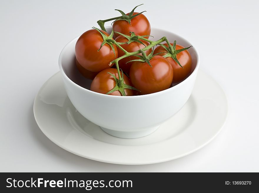White bowl full of vine tomatoes. White bowl full of vine tomatoes