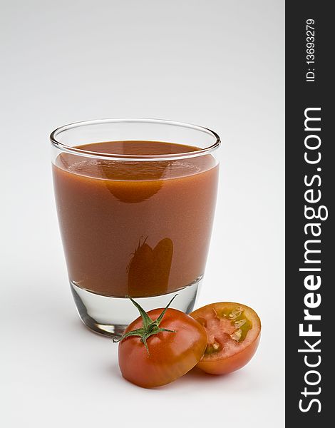 Glass of tomato juice on white with sliced tomato