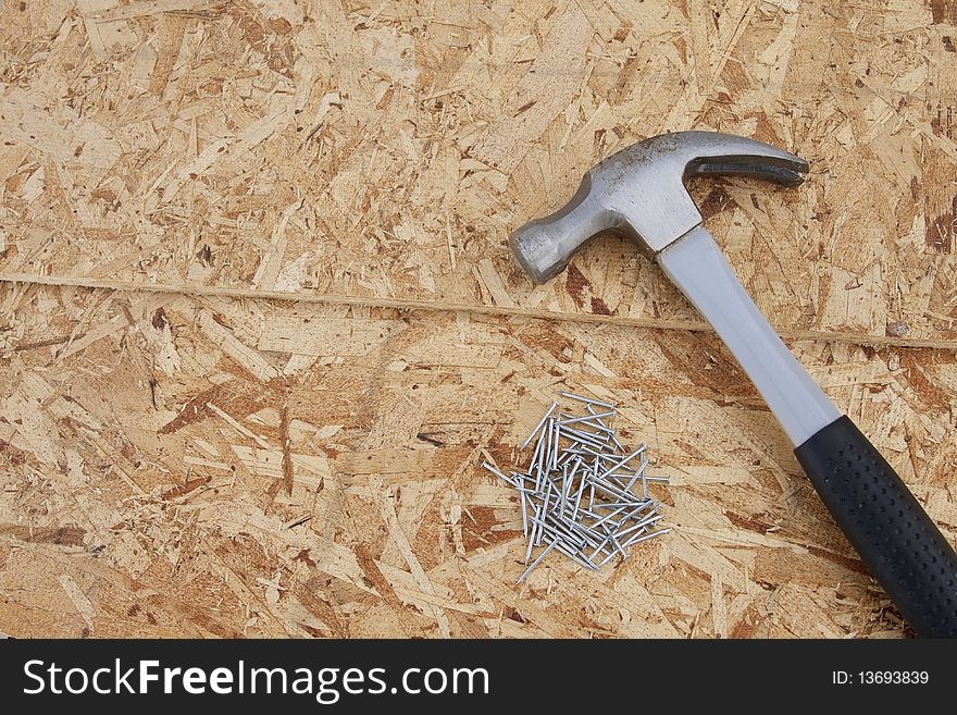 A hammer and a pile of nails ready to be used in construction