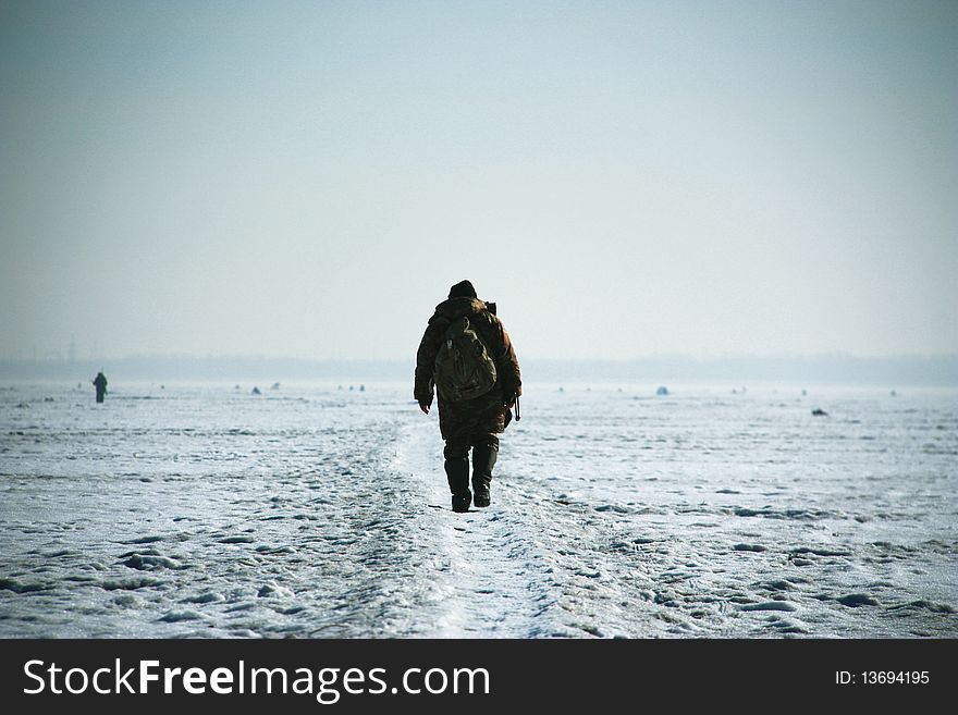 Single fisherman walking on iced lake. Single fisherman walking on iced lake