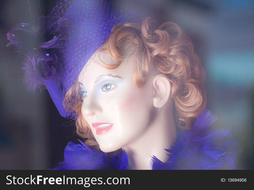 Soft-focus portrait of a female mannequin wearing retro-style purple hat and feathered boa. Soft-focus portrait of a female mannequin wearing retro-style purple hat and feathered boa