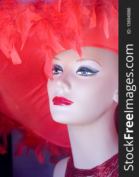 Portrait of a female mannequin wearing a red feathered hat. Portrait of a female mannequin wearing a red feathered hat