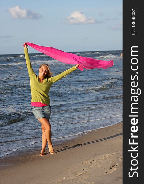 Caucasian blond woman waving ping scarf on beach. Caucasian blond woman waving ping scarf on beach