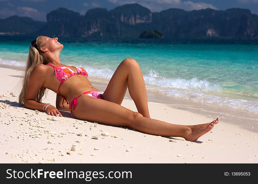 Caucasian blonde woman sitting on a tropical island beach. Caucasian blonde woman sitting on a tropical island beach
