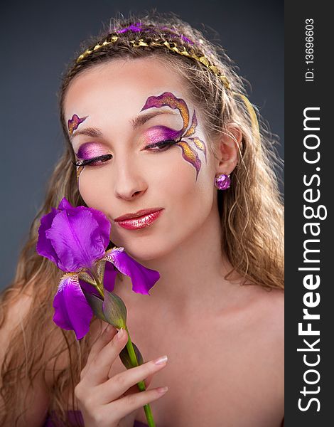 Beautiful girl with bright make-up holding purple iris. Beautiful girl with bright make-up holding purple iris
