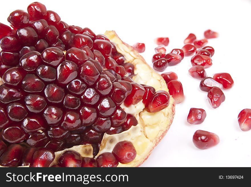 A piece of pomegranate with seeds closeup on white backgound. A piece of pomegranate with seeds closeup on white backgound