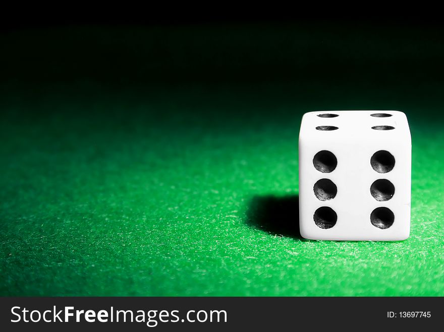 A single die laying on a green felt table