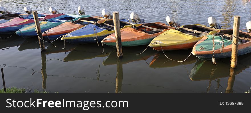 Motor boats to rent on the river; at the end of day (twilight time) are tied in line at the waterside. Motor boats to rent on the river; at the end of day (twilight time) are tied in line at the waterside