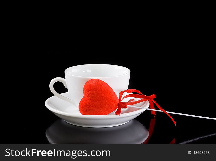 Cup of coffee with red heart on black background