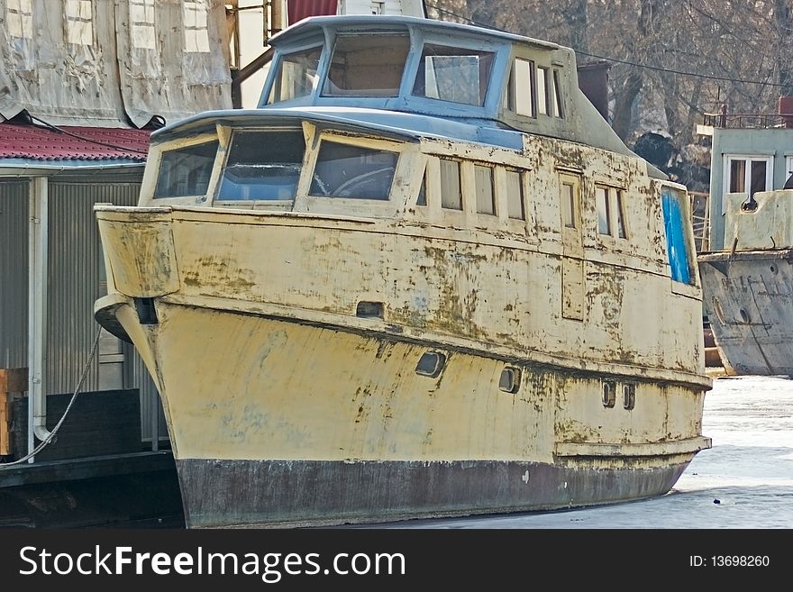 Old boat standing at the dock of the frozen bay