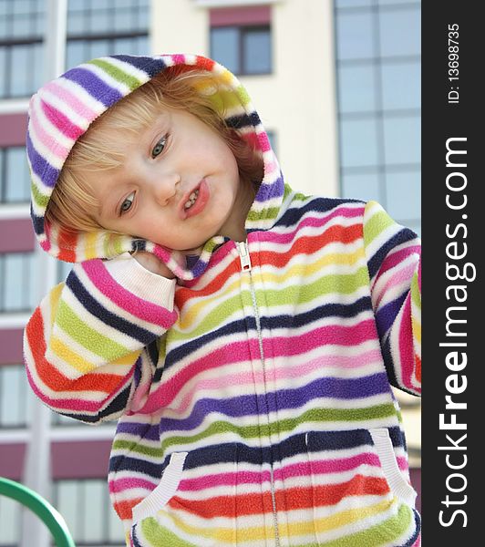 The little girl in a striped hood, against the background of the house. The little girl in a striped hood, against the background of the house