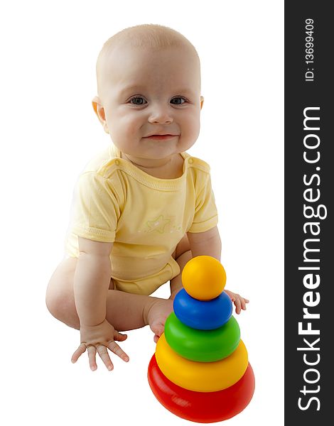 The happy baby smiles and sits next there is a toy a pyramid