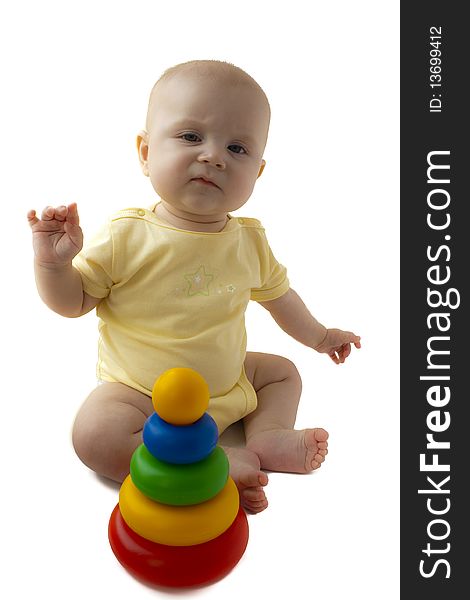 The baby of 6-7 months sits with a pyramid and is angry, hands in the parties